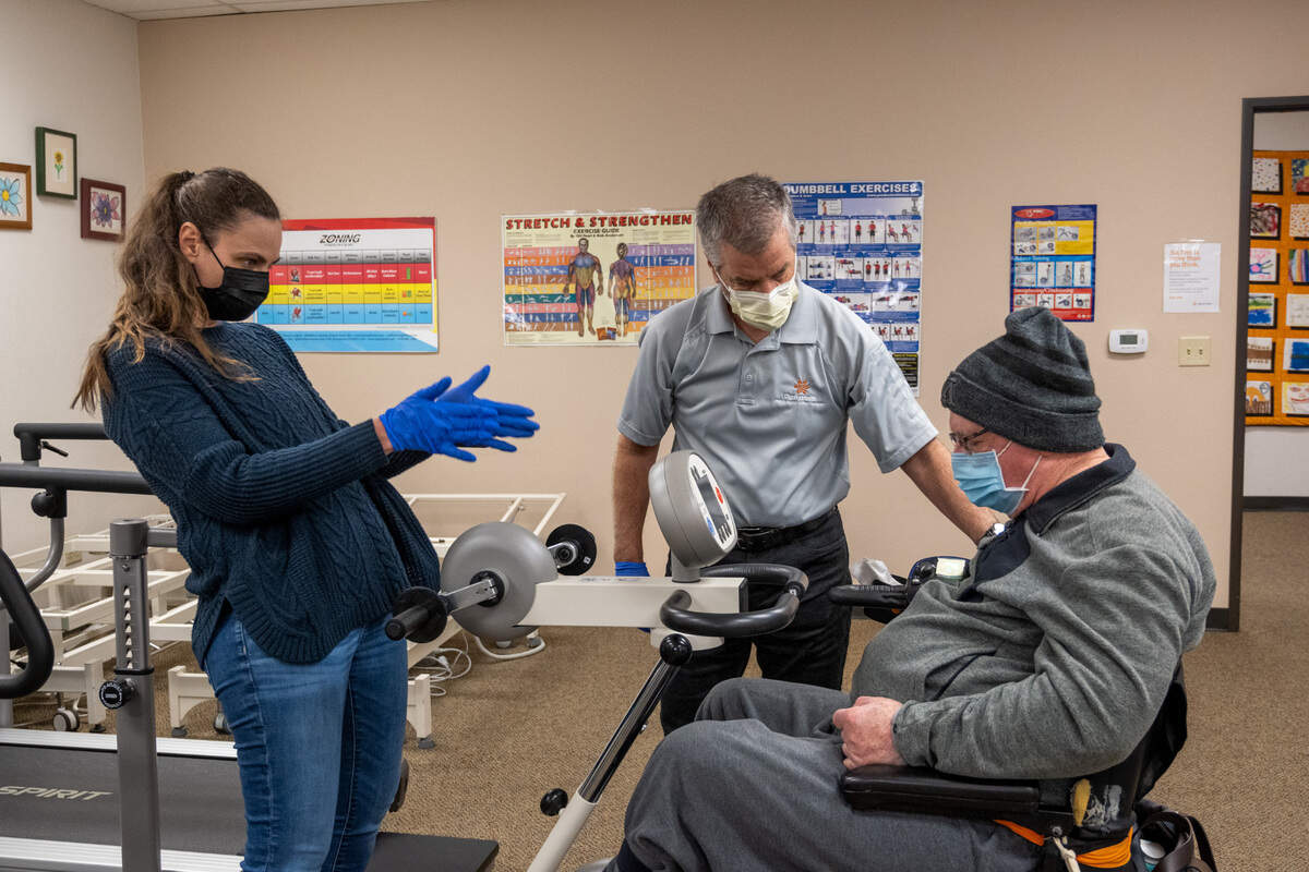 Susan Harcos, left, and Brian Hutchinson, center, Director of the Multiple Sclerosis Achievement Center in Citrus Heights work with Terry Farmer, 78, on a MotoMed machine last month.