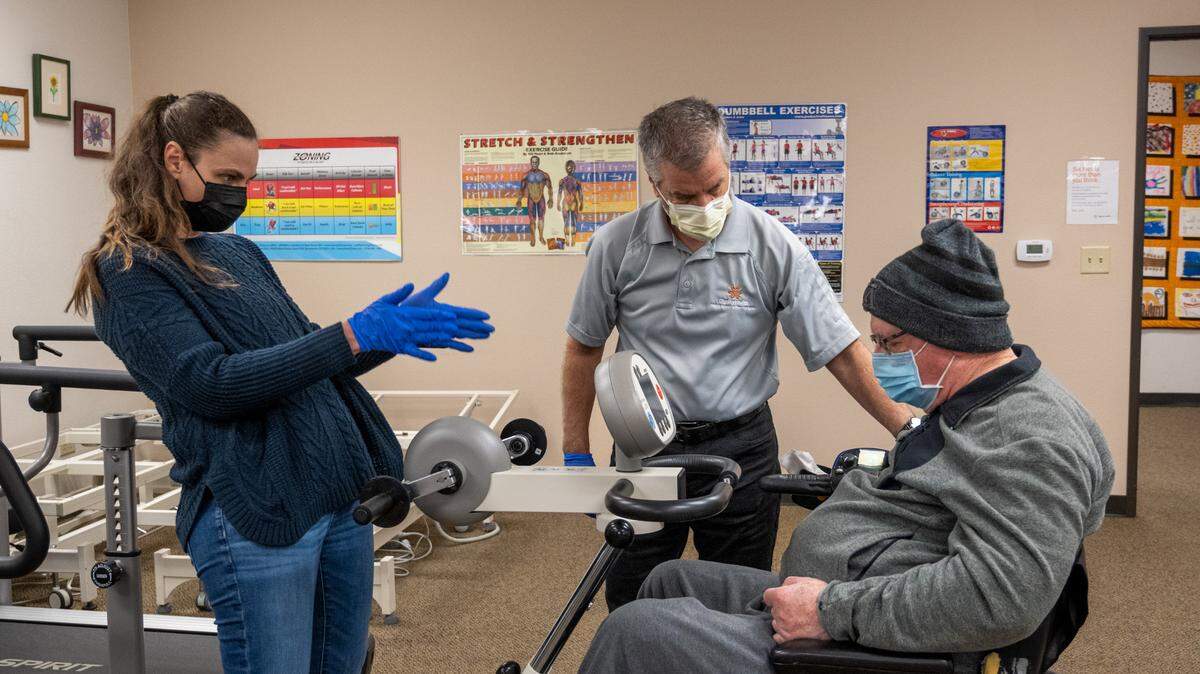 Susan Harcos, left, and Brian Hutchinson, center, Director of the Multiple Sclerosis Achievement Center in Citrus Heights work with Terry Farmer, 78, on a MotoMed machine on Monday, Nov. 28, 2022. Farmer, a former prosecutor, was diagnosed with MS many years ago. The achievement center is asking The Sacramento Bee’s readers for $15,000 in donations through the newspaper’s annual Book of Dreams to upgrade some of its exercise equipment including a second MotoMed that provides movement therapy for people with MS.