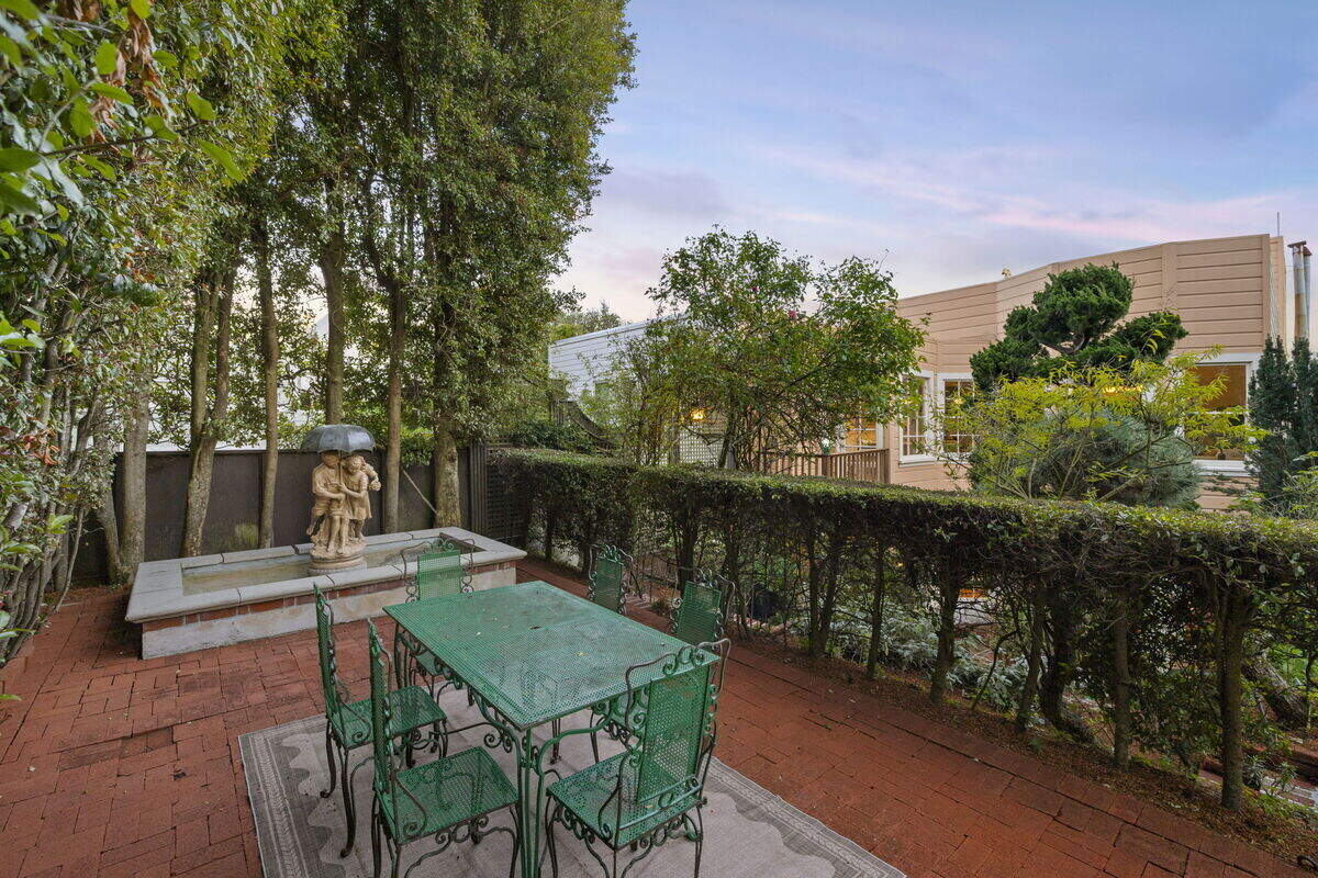 the result of that decades-long stewardship is a series of outdoor rooms stepping away from the house — patios for entertaining, shaded corners for reading, and pathways that reveal new vignettes as you move through the space.