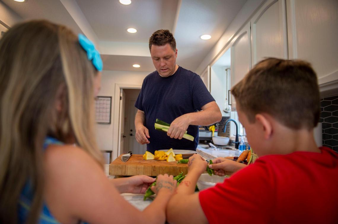 Oliver Ridgeway, 42, chef/owner at Camden Spit + Larder, cuts up vegetables while his children, Camden and Ella Ridgeway, unshell peas in their home in Sacramento.