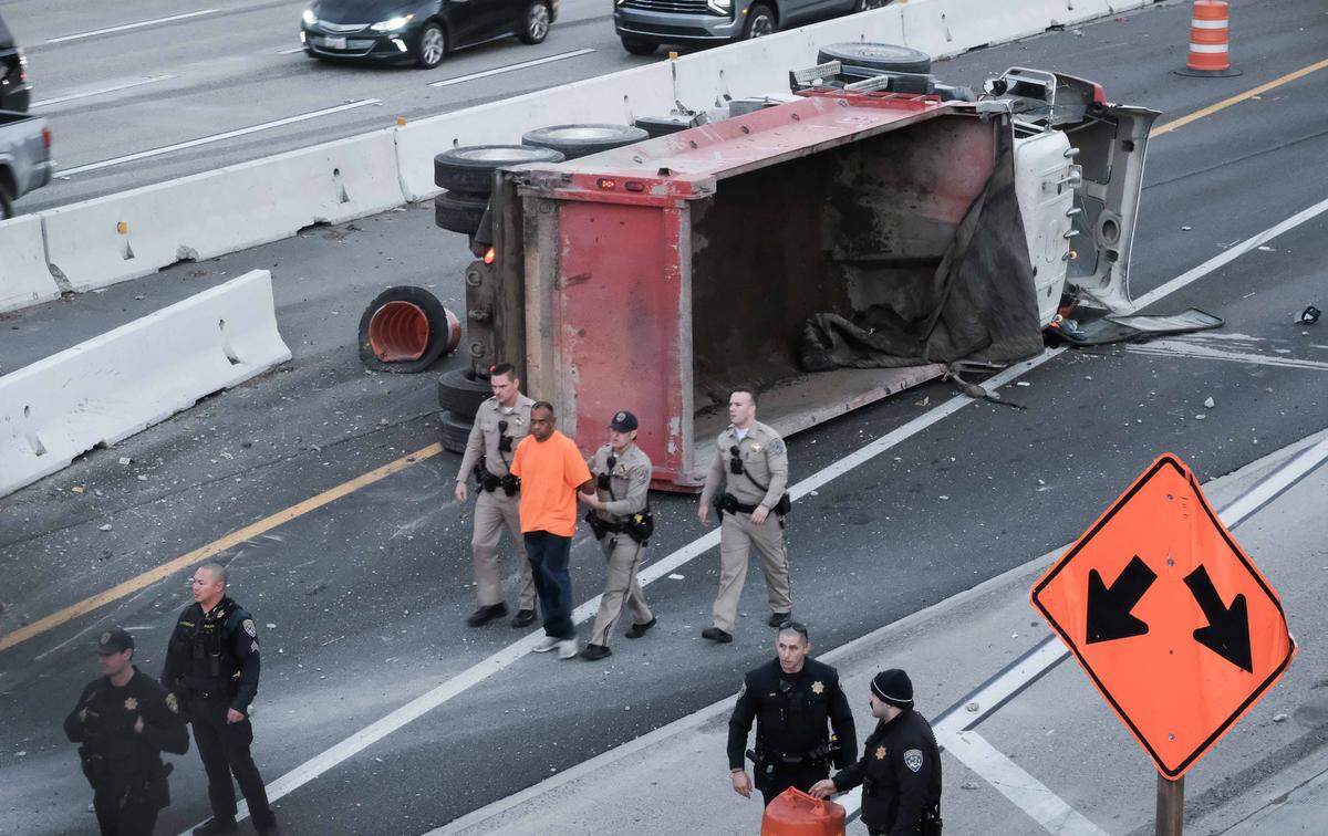 California Highway Patrol officers lead a man away from a crashed dump truck on Highway 50 in Sacramento on Wednesday.