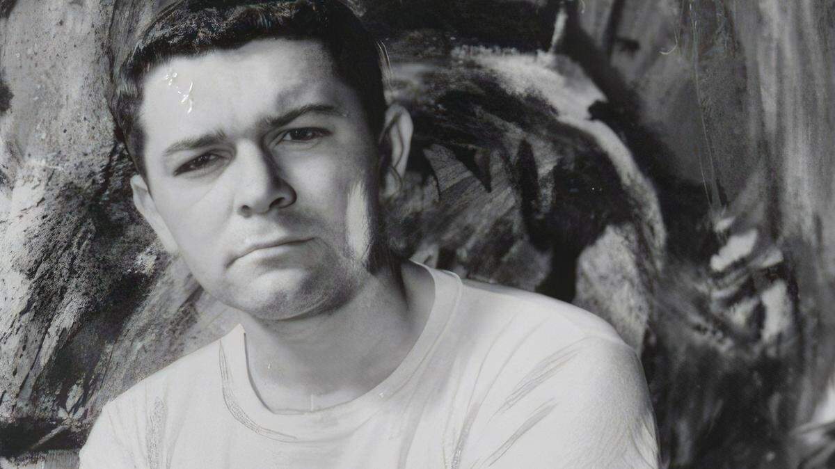 Sacramento artist Mel Ramos holds a paint brush as he sits in front of a painting in 1966.