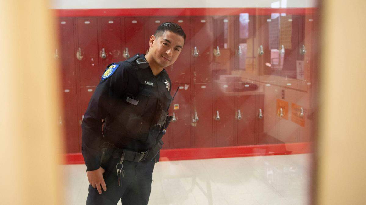 School resource officer Anthony Hoang looks through the window of an empty classroom at C.K. McClatchy High School in Sacramento on in December 2019. A new PPIC poll finds 7 in 10 adults support schools having armed police officers on campus.