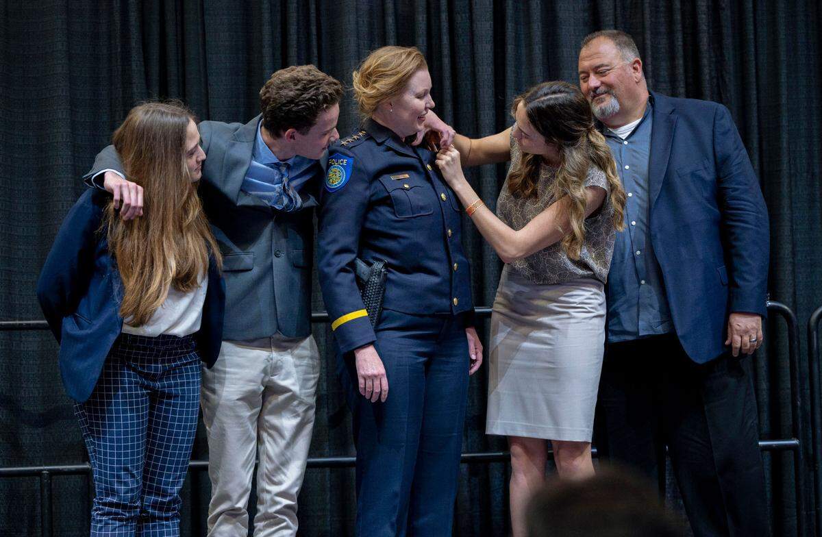 Sacramento Police Chief Kathy Lester has her badge pinned by daughter Jacklyn Hughes while standing on stage with her other children Hannah, left, and Liam and her husband Keith Hughes, right, during her swearing in ceremony at Golden 1 Center in Sacramento on March 17, 2022.
