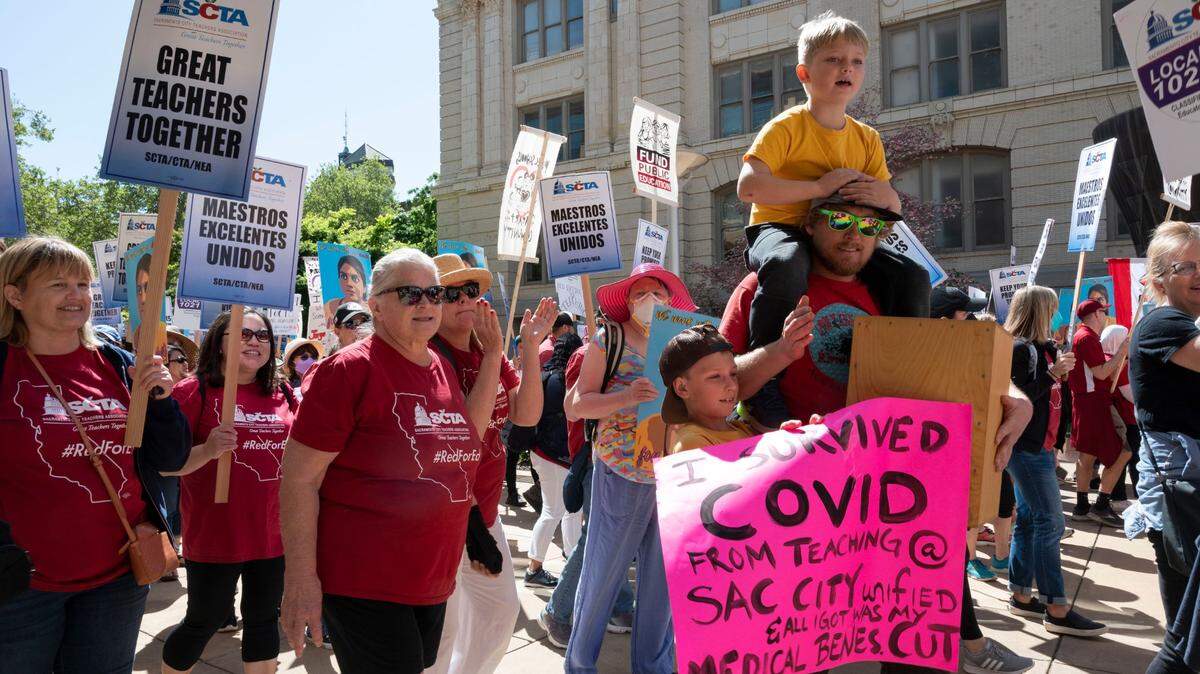 Taylor Cavin, right, a teacher at AM Winn Public Walforf marches at City Hall with his two kids, Felix, 6, on his shoulders, and Aulin, 9, who holds a sign for his dad, on Day 3 of the Sacramento City teachers’ strike Friday, March 25, 2022.
