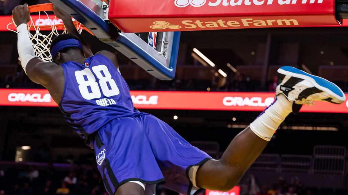 Sacramento Kings center Neemias Queta (88) hangs on the rim after dunking over Golden State Warriors guard Lester Quiñones (25) during the fourth period at the California Classic NBA preseason basketball game Saturday, July 2, 2022, at Chase Center in San Francisco.