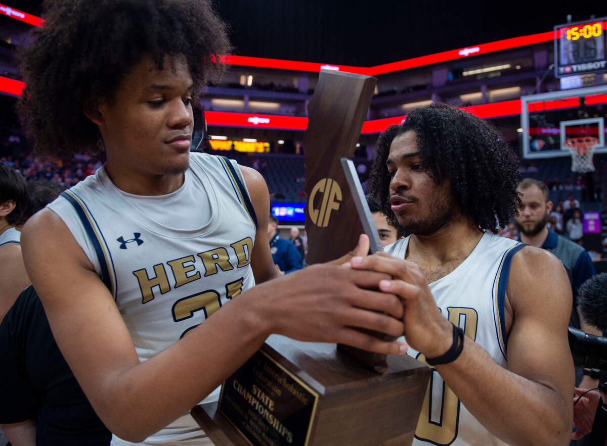 Elk Grove’s DaJon Lott Jr., left and Ameere Britton carry the CIF State Division II championship trophy after winning against Foothill of Santa Ana on Saturday, March 12, 2022, at Golden 1 Center in Sacramento.