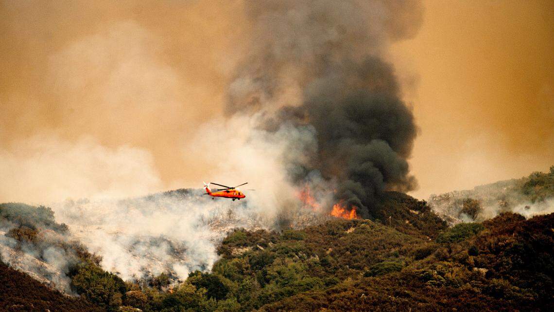 A helicopter prepares to drop water on the KNP Complex Fire in Sequoia National Park, Calif., on Wednesday, Sept. 15, 2021. The blaze is burning near the Giant Forest, home to more than 2,000 giant sequoias. (AP Photo/Noah Berger)