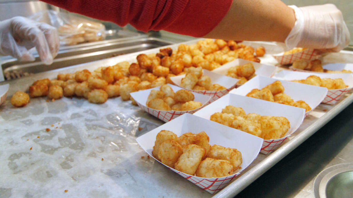 In this Nov. 16, 2012 photograph, a cafeteria worker at Stonebridge Elementary School in Brandon, Miss., gathers steam-cooked tater tots for students’ lunch. The tater tot is an essential element in many a casserole.