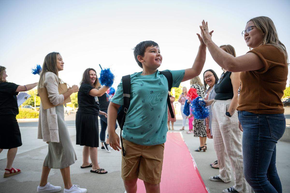 Riley, a student at Navigator Elementary in Rancho Cordova, high fives teacher Emily O’Brien on Tuesday, Aug. 8, 2023, as staff welcome returning students back from summer vacation with a red carpet treatment.