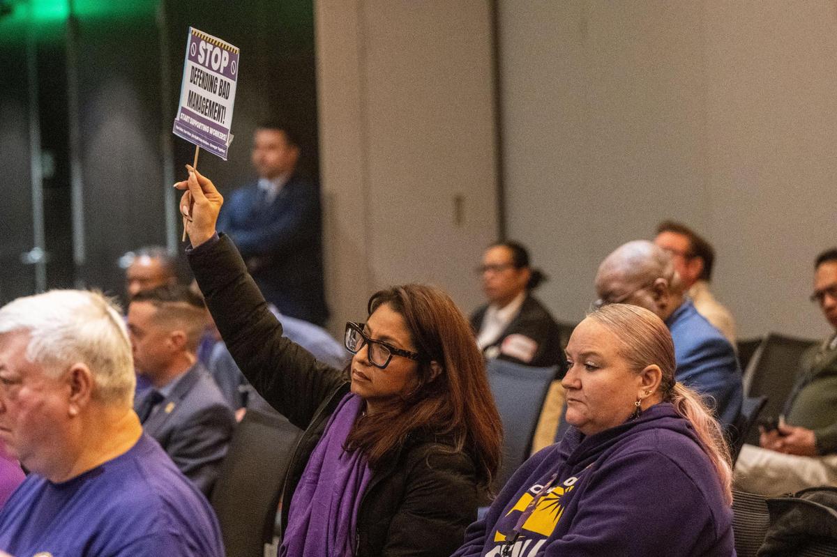 Anica Walls, the new president of SEIU Local 1000, holds a sign that reads “stop defending bad management” during a California State Lottery Commission meeting on Thursday.