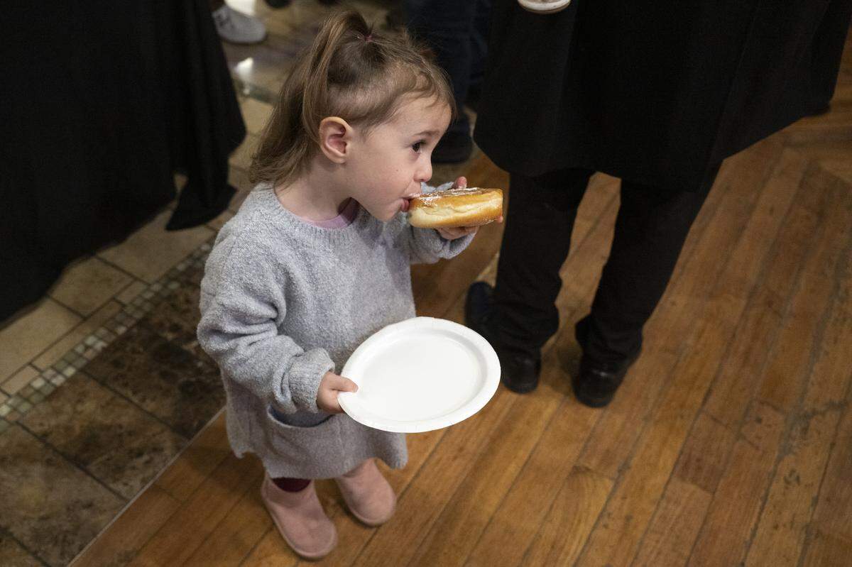 Shaina Korik, 2, eats a jelly filled donut during a menorah lighting on the first night of Hanukkah at the Westfield Galleria in Roseville on Sunday.