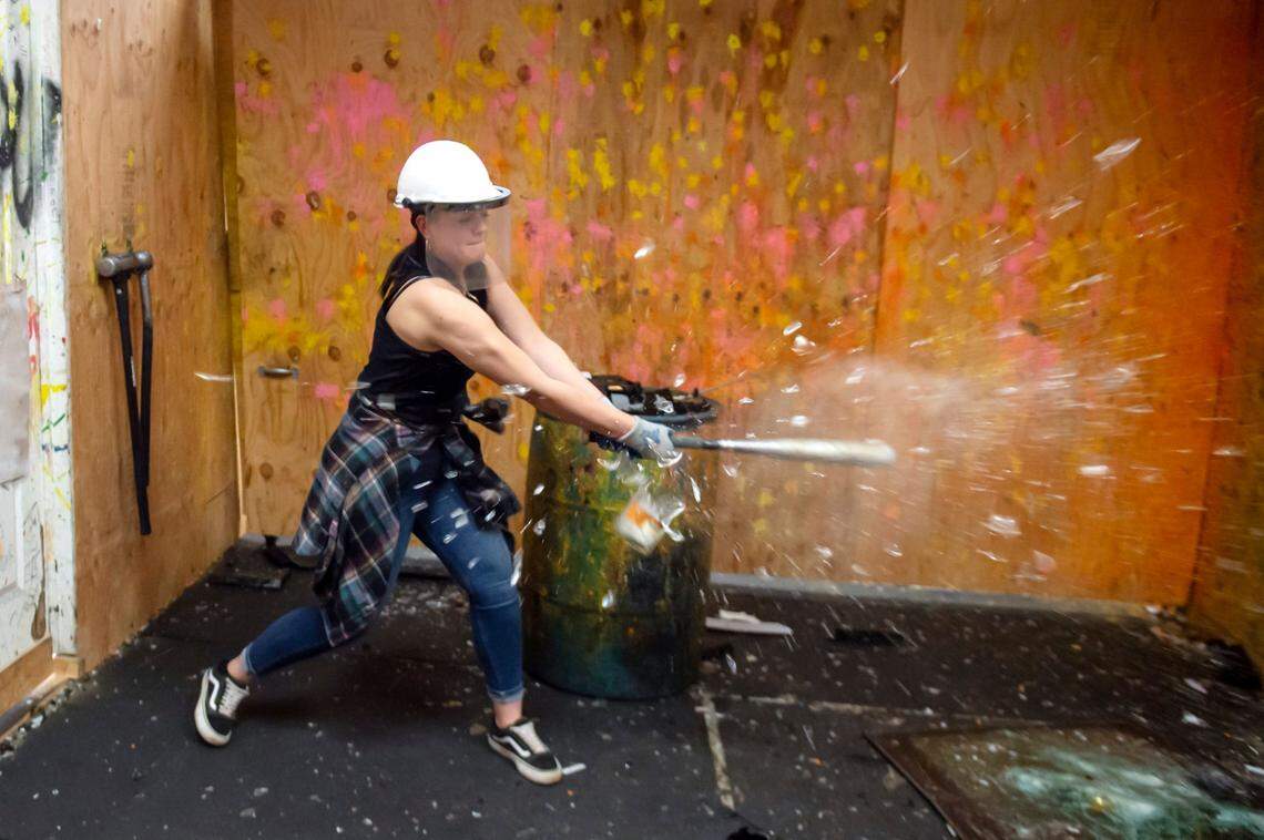 Mandy Netherby shatters a bottle with a baseball bat at the original Smash Sacramento location in Carmichael on Monday, Sept. 20, 2021. Her uncle, Carnagy Hall, brought her and her aunt Tammy Hall to the “rage room,” a safe environment to break glass and other things without the hassle of cleaning up.