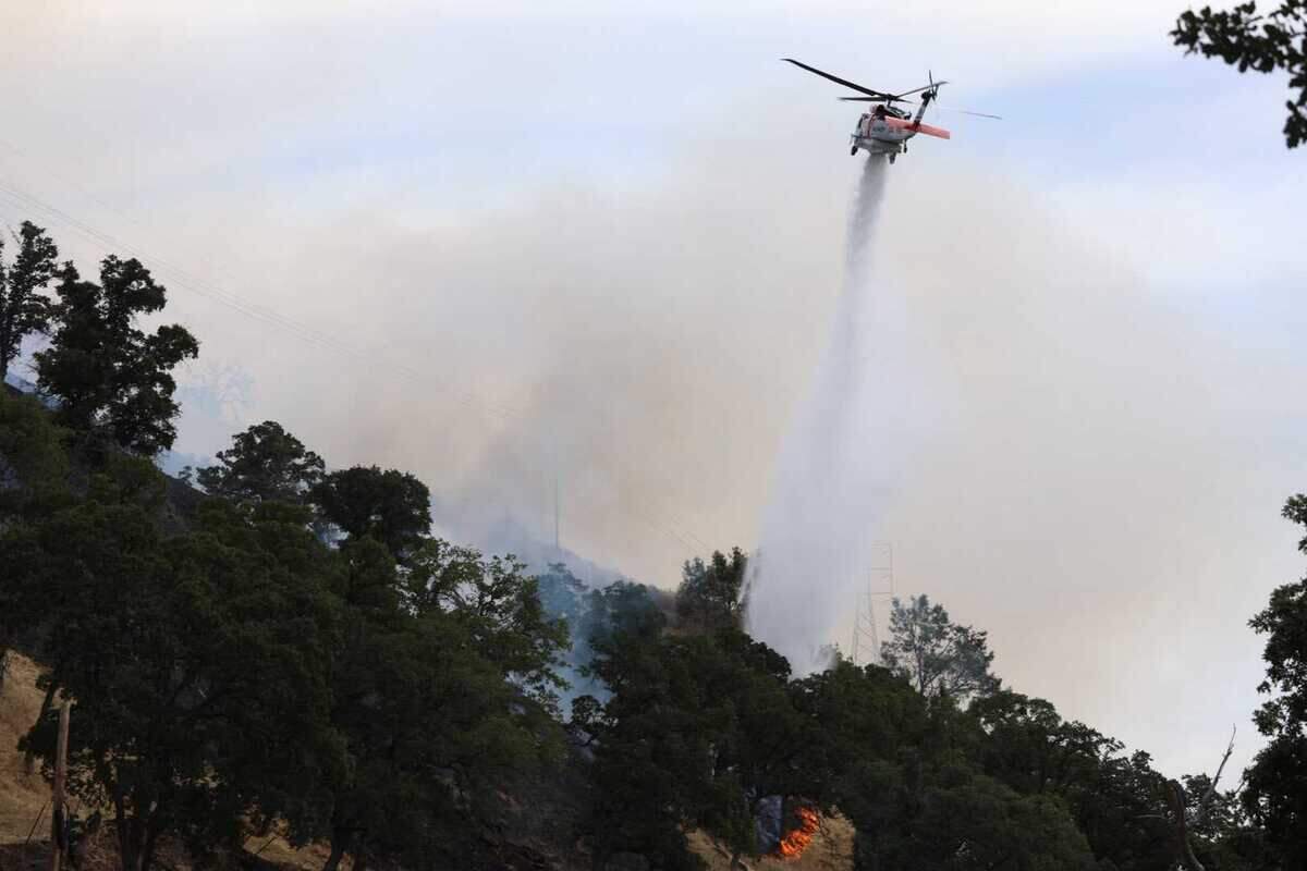 A helicopter drops water on the Putah Fire burning near Winters in Yolo County on Monday, June 8, 2026. The fire jumped to 300 acres in roughly three hours, according to Cal Fire.