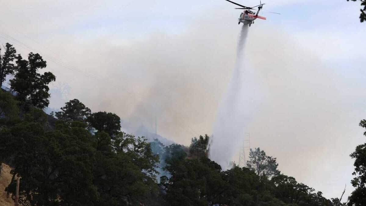 A helicopter drops water on the Putah Fire burning near Winters in Yolo County on Monday, June 8, 2026. The fire jumped to 300 acres in roughly three hours, according to Cal Fire.