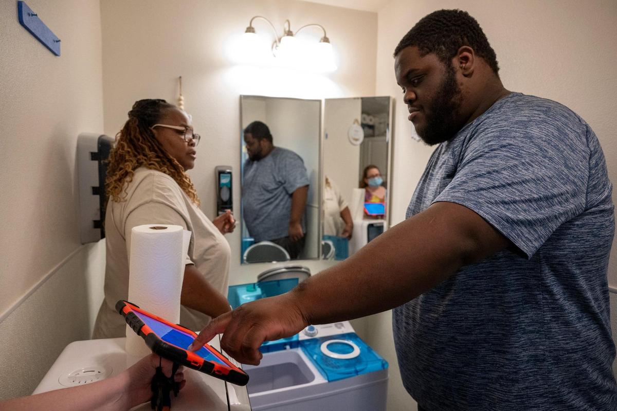 Benita Shaw Ayala’s 21-year-old autistic and non-verbal son, Christopher, works with augmentative communications specialist Jennifer Beckett using a communication device as he learns to use a washing machine at The Gift Foundation center in Citrus Heights on Wednesday.