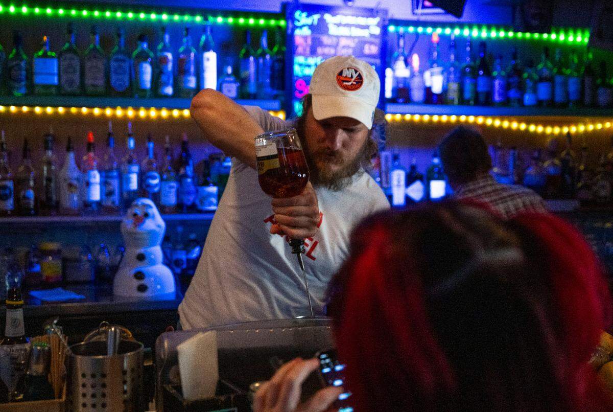 Golden Bear bartender Clifford Jaynes pours a cocktail on Saturday in midtown. The owners of the business support a proposal the Sacramento City Council will consider that would allow bars and restaurants to sell open containers of alcohol for patrons to take out onto streets during designated events.
