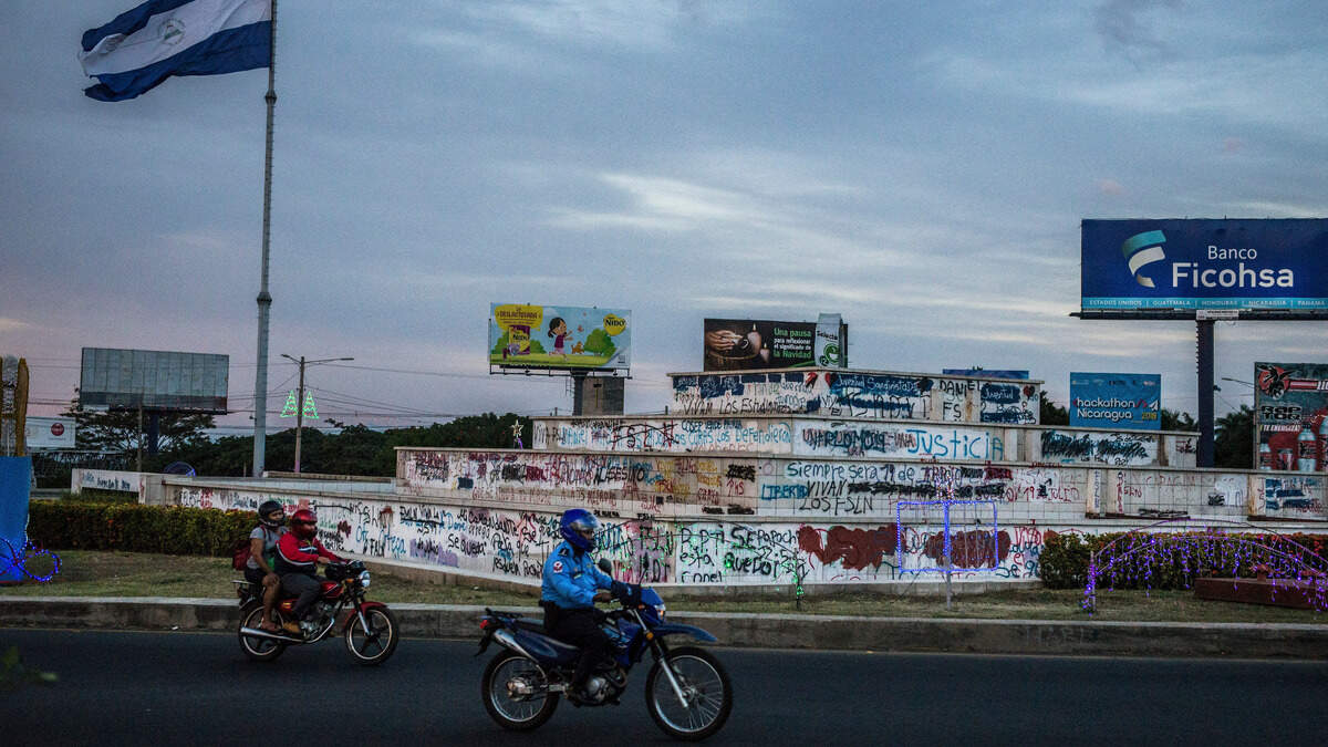 A Nicaraguan flag flying over a traffic circle that was the site of numerous opposition rallies, and where paramilitaries painted over antigovernment graffiti along the street, in Managua, Nicaragua, Dec. 21, 2018. When huge protests demanded that he leave office, President Daniel Ortegas days seemed numbered. But his repressive response has sent thousands into hiding and tightened his hold on power. (Meridith Kohut/The New York Times)