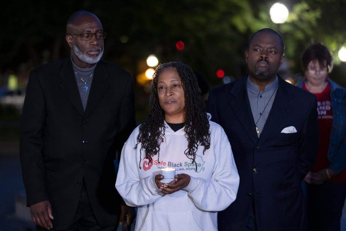 Kristee Haggins, board president of Safe Black Space, center, talks holds a candle at an impromptu vigil at Cesar Chavez Plaza on Sunday night after the mass shooting in downtown Sacramento.
