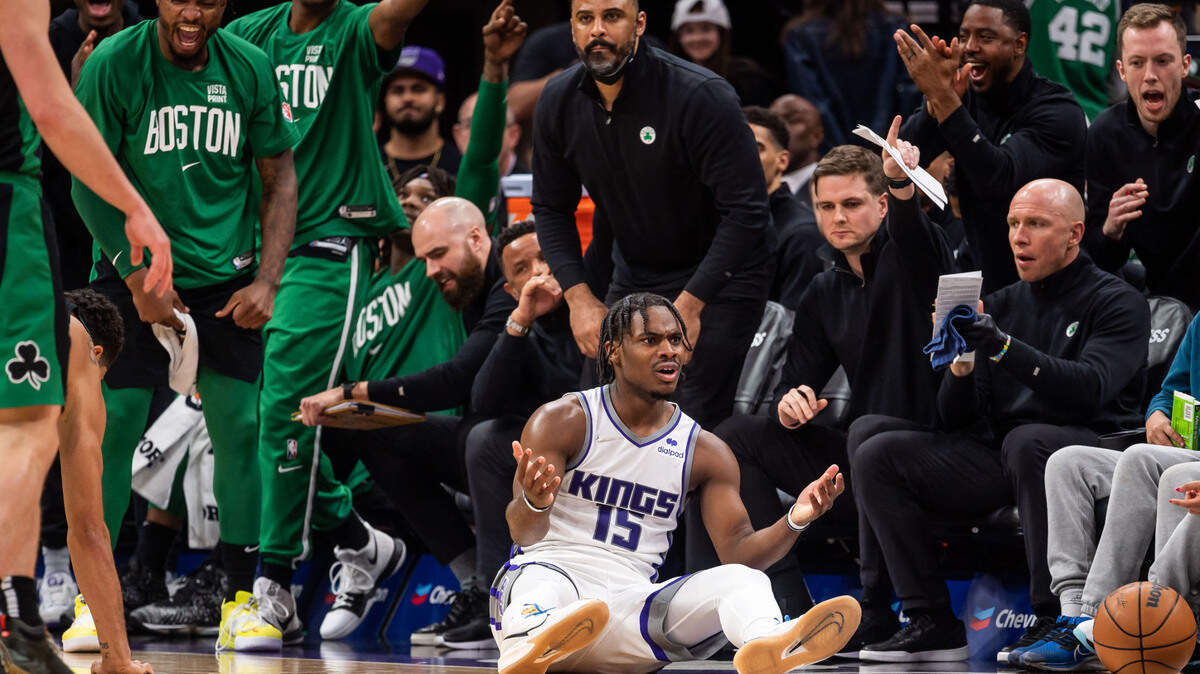 Sacramento Kings guard Davion Mitchell (15) looks to officials for a foul call after falling following contact with Boston Celtics forward Jayson Tatum (0) during the second period at the NBA basketball game Friday, March 18, 2022, at Golden 1 Center in Sacramento. Boston Celtics head coach Ime Udoka stands with his team from the bench behind Mitchell.