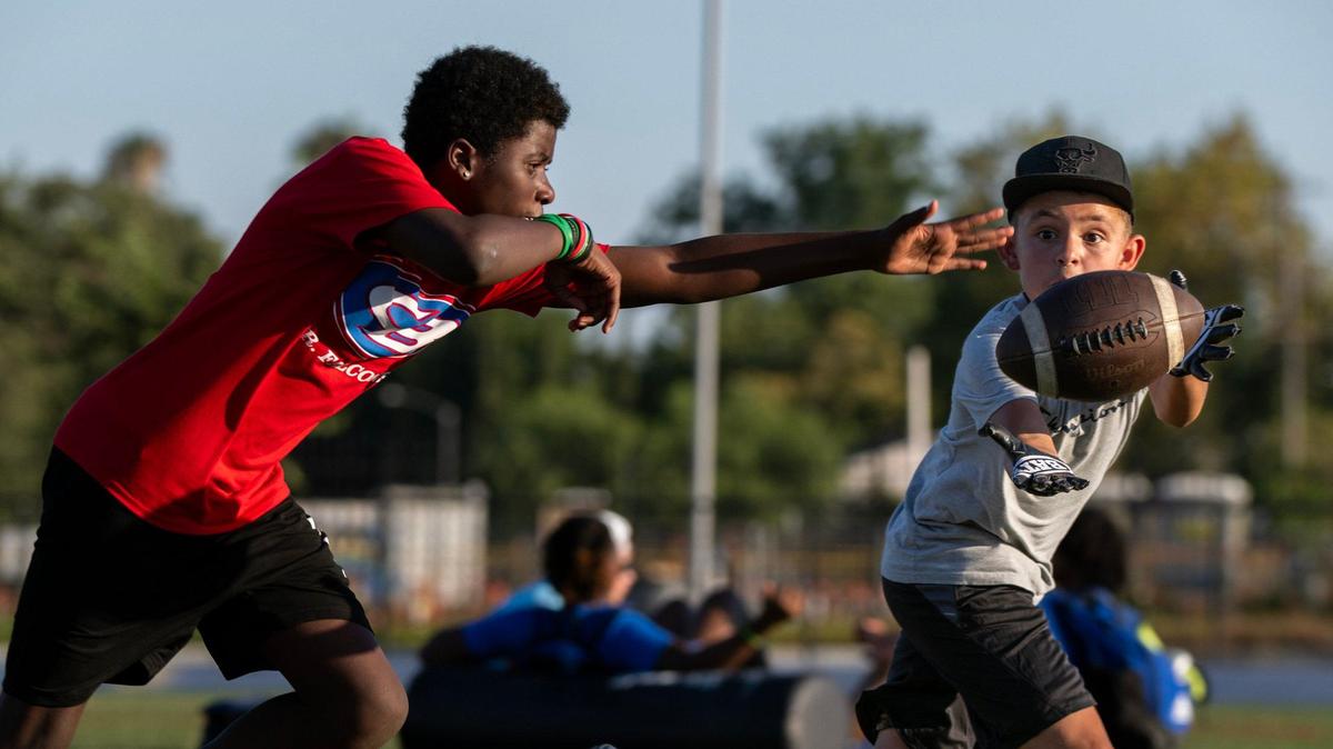 Billy-Crez Delgado, 11, makes a catch in front of Antione Estes-Dyson, 13, during drills at the Spencer Webb Youth Football and Cheer Camp in July 2024 at Christian Brothers High School.