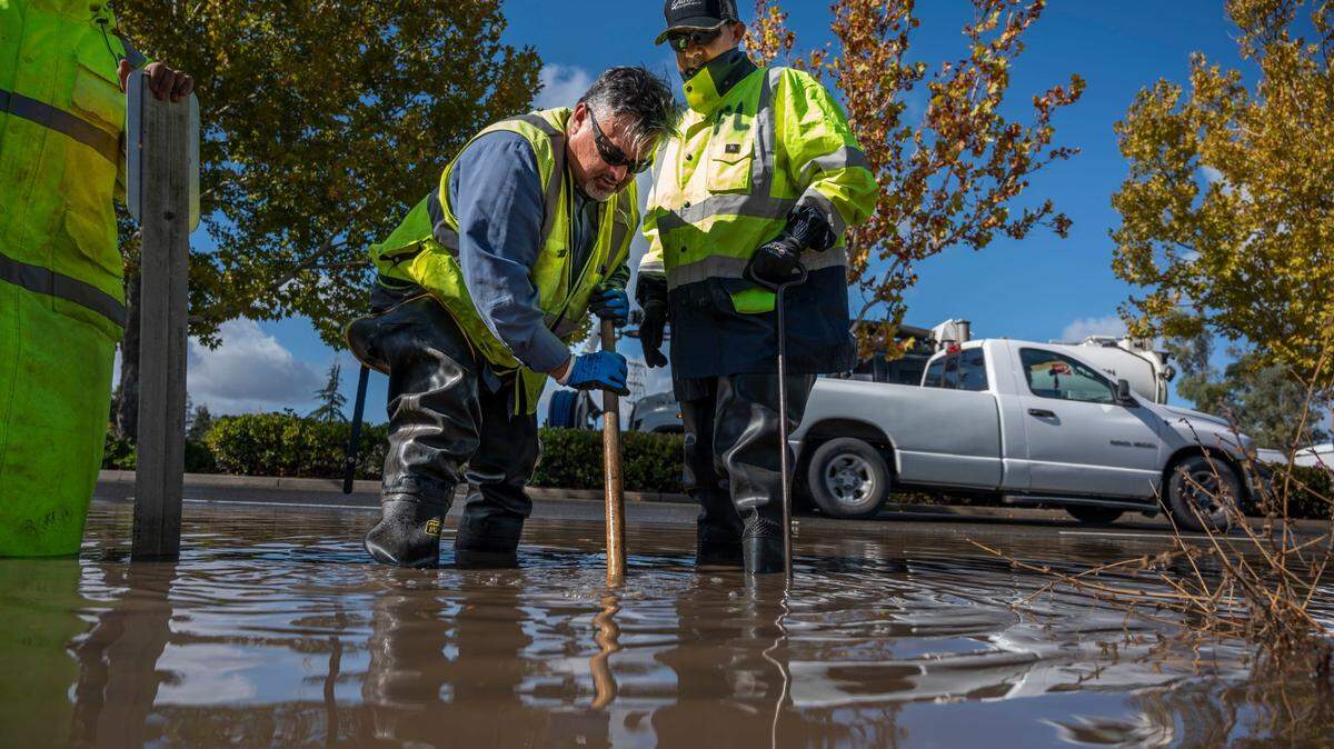 Jesus Garcia a storm equipment operator for Sacramento County feels for debris in a drain on Power Inn Rd. Near Stevenson Ave. on Monday, Oct. 25, 2021 a day after a storm brought more than five inches of rain to the area. Garcia took turns with Fernandino Luna, right a senior storm utility worker pulling debris as they cleared the water.