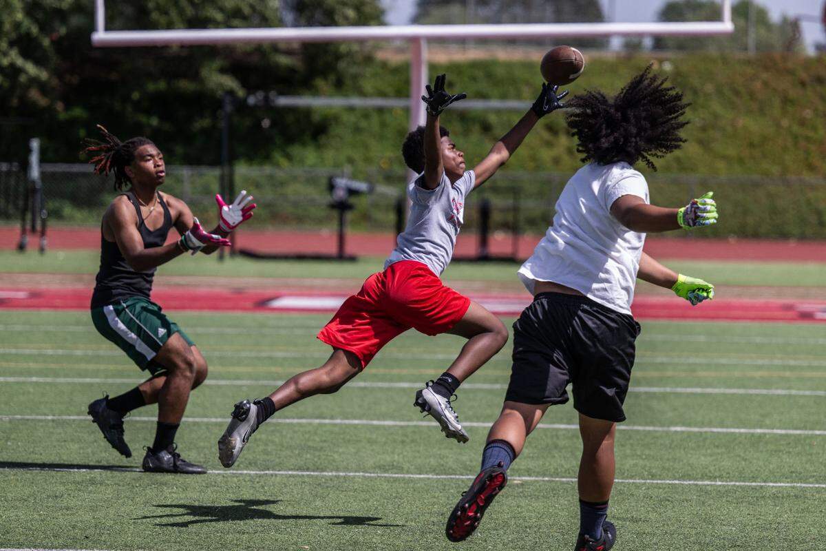 Cordova High School football player Taimarr Johnson, left, defends Terryn Kings, center, as he reaches for the ball during spring training on Monday, May 20, 2024.