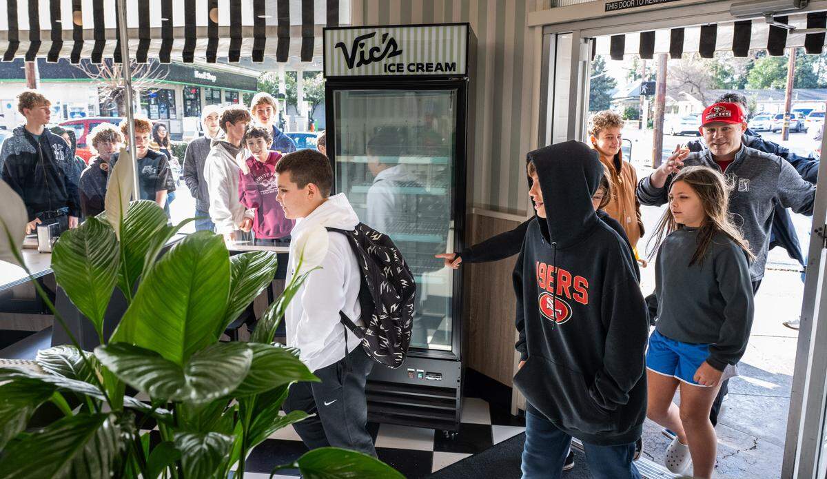 Trey Olson, 12, left, and Owen Counts, 11, enter Vic’s Ice Cream in Sacramento on Saturday after being the first in line for the shop’s 11 a.m. reopening. The pair said they lined up at around 9. Trey’s father Ted, wearing a 49ers hat at right, worked as a server as a teen. 