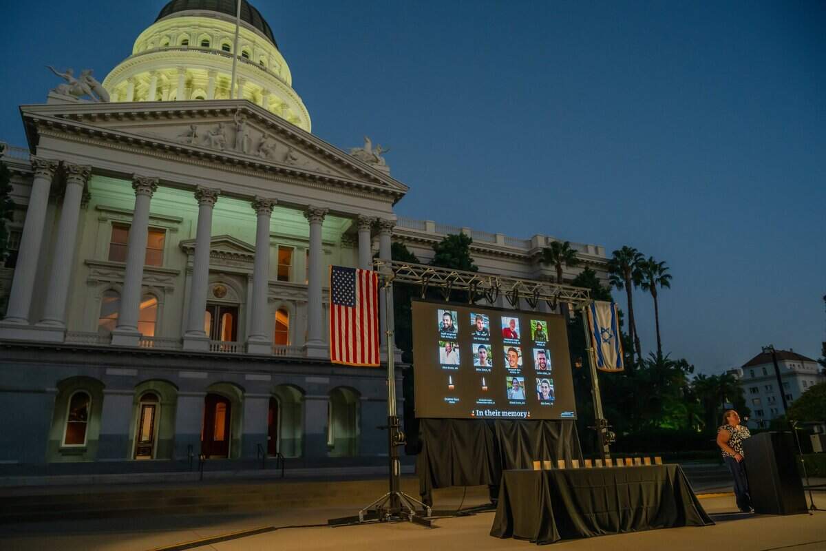 Marieta Socolovsky, CEO of The Jewish Federation of the Sacramento Region, speaks at a Jewish community gathering on Monday at the state Capitol to mark the one-year anniversary of the Hamas attack on Israel. Pictures were projected above candles that were lit by family members, regional rabbis and cantors.