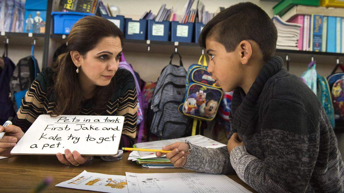 Bilingual instructional aide Dalya Abdullah helps Ali Al-Shaban, 6, in his first grade class last year. The number of refugee students in San Juan Unified has soared in recent years, boosting demand for instructors for English learners whose native languages include Arabic, Farsi, Dari and Pasto.