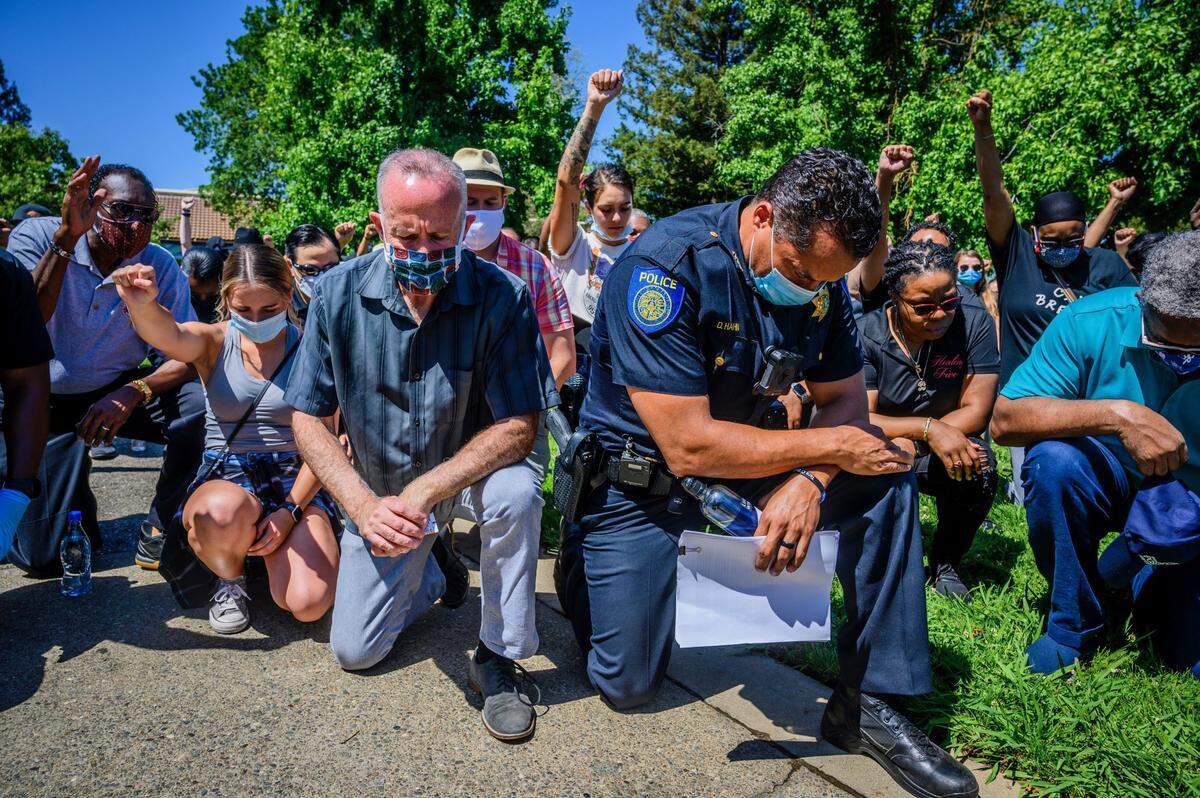 Sacramento Police Chief Daniel Hahn and Mayor Darrell Steinberg kneel in June 2020 with a large group of demonstrators in Sacramento’s Oak Park neighborhood in a display of unity as another day of protests over the death of George Floyd was planned in the capital.