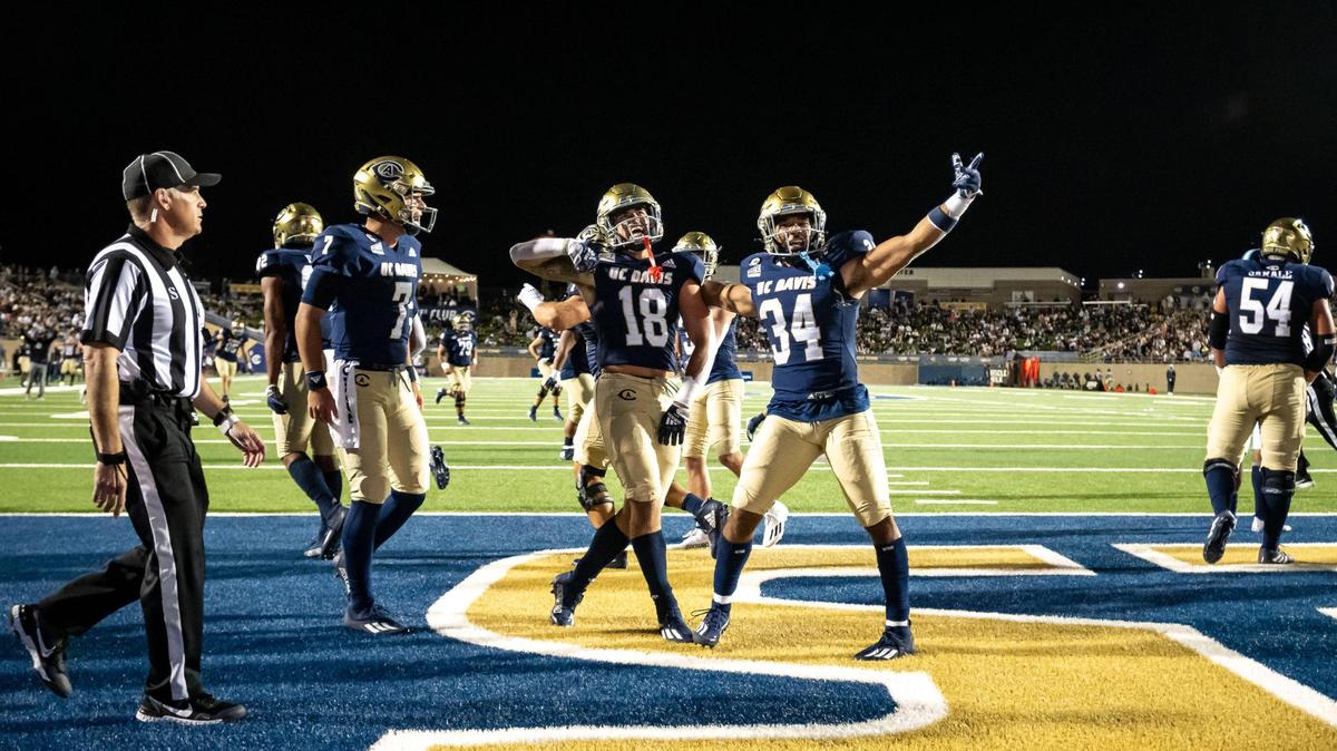 UC Davis Aggies athlete Trent Tompkins (18), center, is celebrated by teammates, running back Ulonzo Gilliam Jr. (34), right, and quarterback Miles Hastings (7), left, for his touchdown run during the second quarter against the San Diego Toreros in their NCAA college football home opener Saturday, Sept. 17, 2022, at UC Davis Health Stadium.