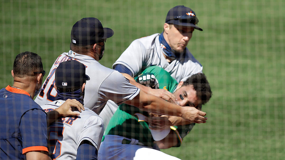 Oakland Athletics’ Ramon Laureano is restrained by Houston Astro’s Dustin Garneau after Laureano charged the dugout after being hit by a pitch thrown by Humberto Castellanos in the seventh inning of a baseball game Sunday, Aug. 9, 2020, in Oakland, Calif. (AP Photo/Ben Margot)