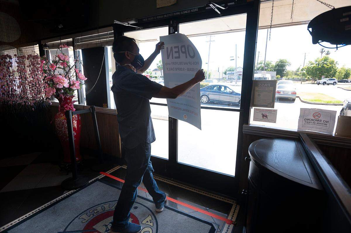 Pho Bac Hao Viet restaurant owner Dao Ut removes a sign for take-out as he prepares to open the restaurant to dine-in customers on Thursday, May 28, 2020, in Sacramento’s Little Saigon area during the coronavirus pandemic.