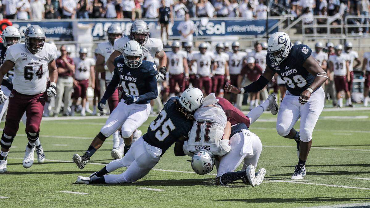 Montana quarterback Dalton Sneed is tackled by UC Davis defenders Saturday in Davis. The visiting Grizzlies beat the Aggies 45-20 in a Big Sky Conference opener.