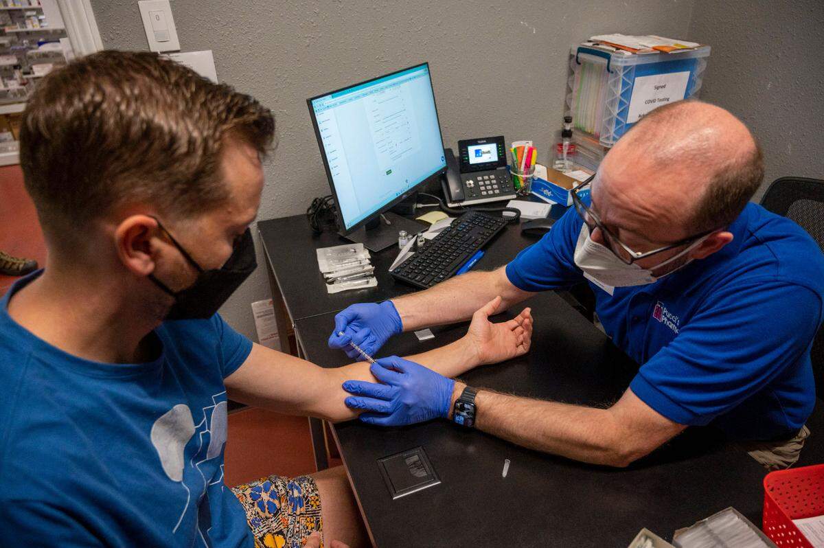 Beau Davenport, left, gets a monkeypox vaccination from Clint Hopkins at Pucci’s Pharmacy in East Sacramento on Wednesday. Hopkins said he felt giving monkeypox vaccinations was the right thing to do for their customers and the community, even though his pharmacy hasn’t been reimbursed from insurers.