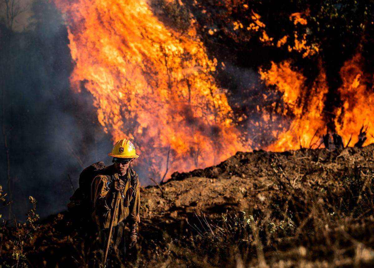 Logan Powell, with a Cal Fire crew from the Amador-El Dorado unit, keeps an eye on hot spots as the Mosquito Fire makes its way up a hill south of Wortons Market in Foresthill on Tuesday, Sept. 13, 2022.