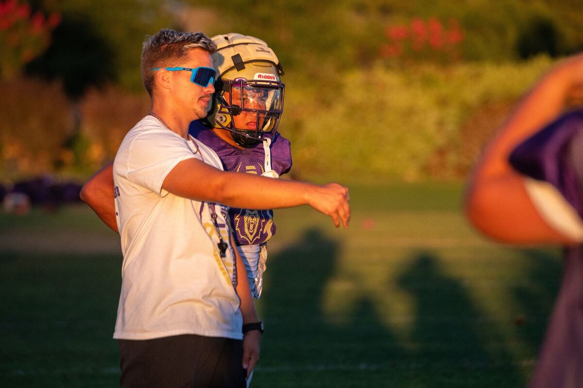 Assistant coach Philip Conner, left, speaks with running back Mateo Mojica, right, during practice at Bradshaw Christian High School in Vineyard on Monday. “I feel like I get enough praise as is,” Mojica said. “But people don’t see my teammates that work – the linemen that block for me.”