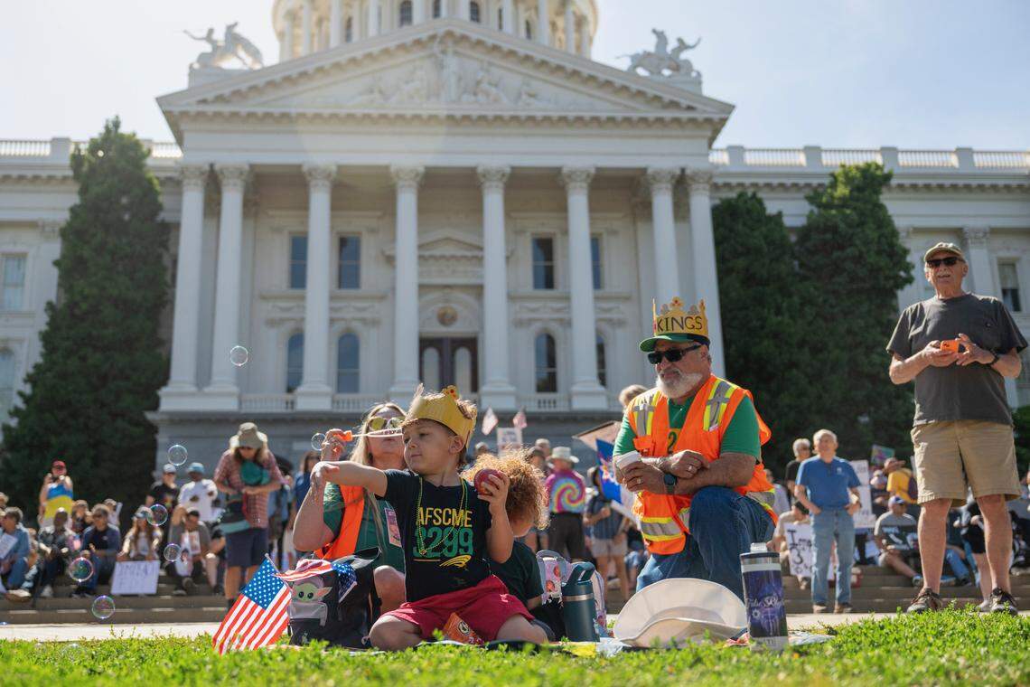 Amy, left, Kyler, 4, center left, and Arora, 2, center right, and Joseph Small sit in front of the state Capitol before the “No Kings” protest against President Donald Trump in Sacramento on Saturday.