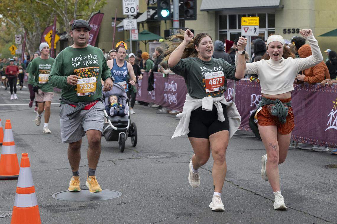 Runners cross the finish line of the 10k race during the Run to Feed the Hungry in Sacramento on Thursday, Nov. 27, 2025.