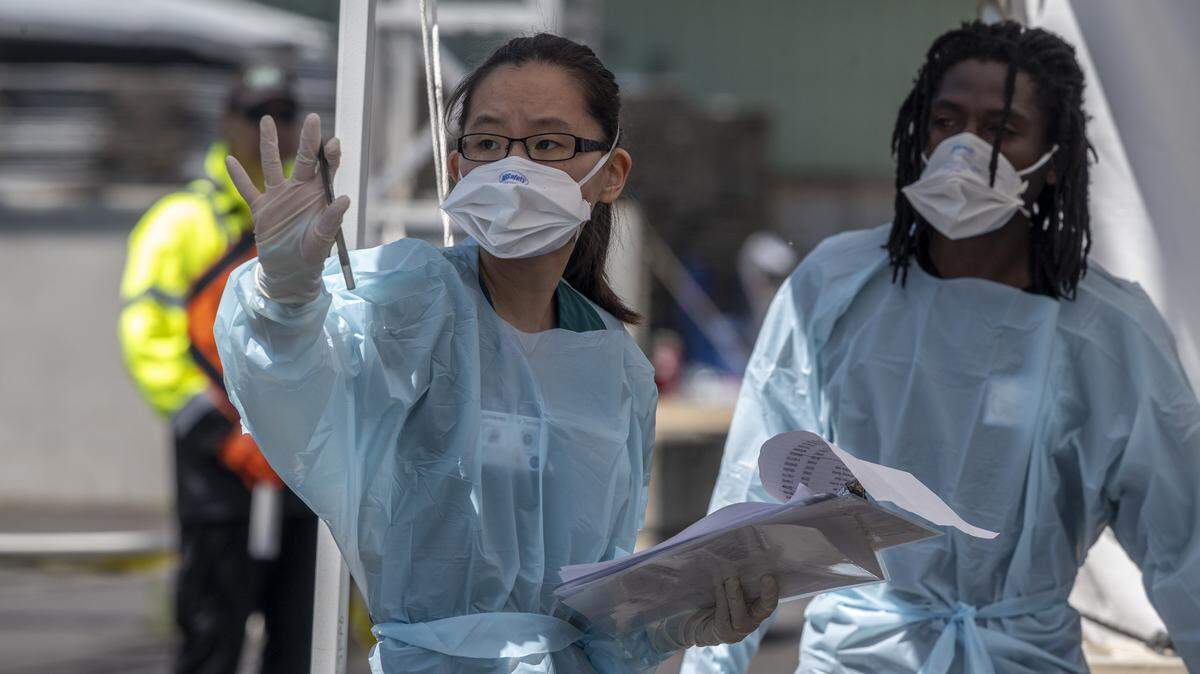 Nomin Nyamkhuu, left, nursing student at Sacramento State, stops a car as she works at the check in station for coronavirus testing at Cal Expo in Sacramento on Wednesday, April 15, 2020.