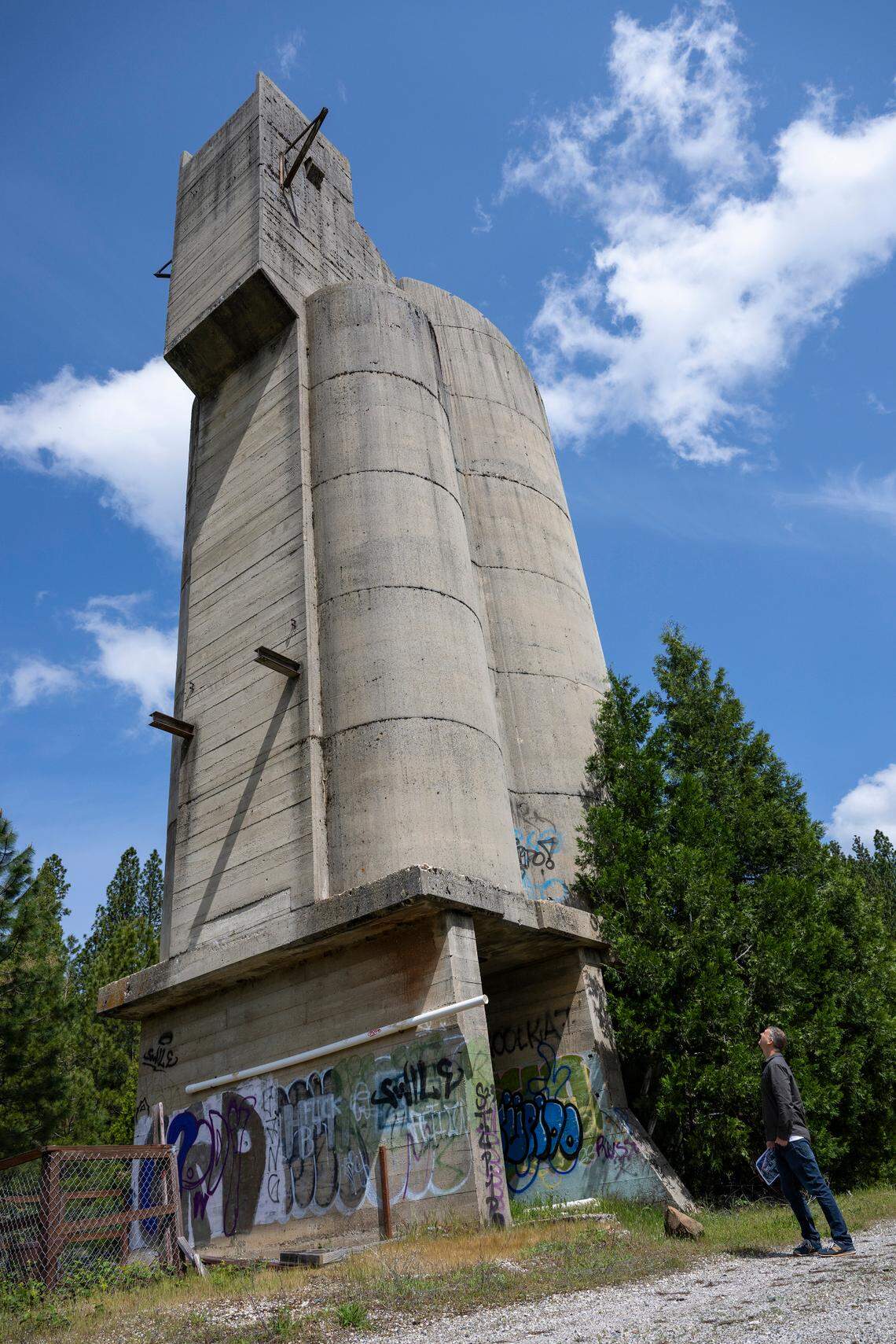 Rise Gold Corp. CEO Ben Mossman looks up in May at the silo from the historic Idaho-Maryland Mine near Grass Valley that would be reused if the mine were to reopen. In the fenced area at the structure’s base is the vertical shaft, long covered, that drops about 3,400 feet below the surface.