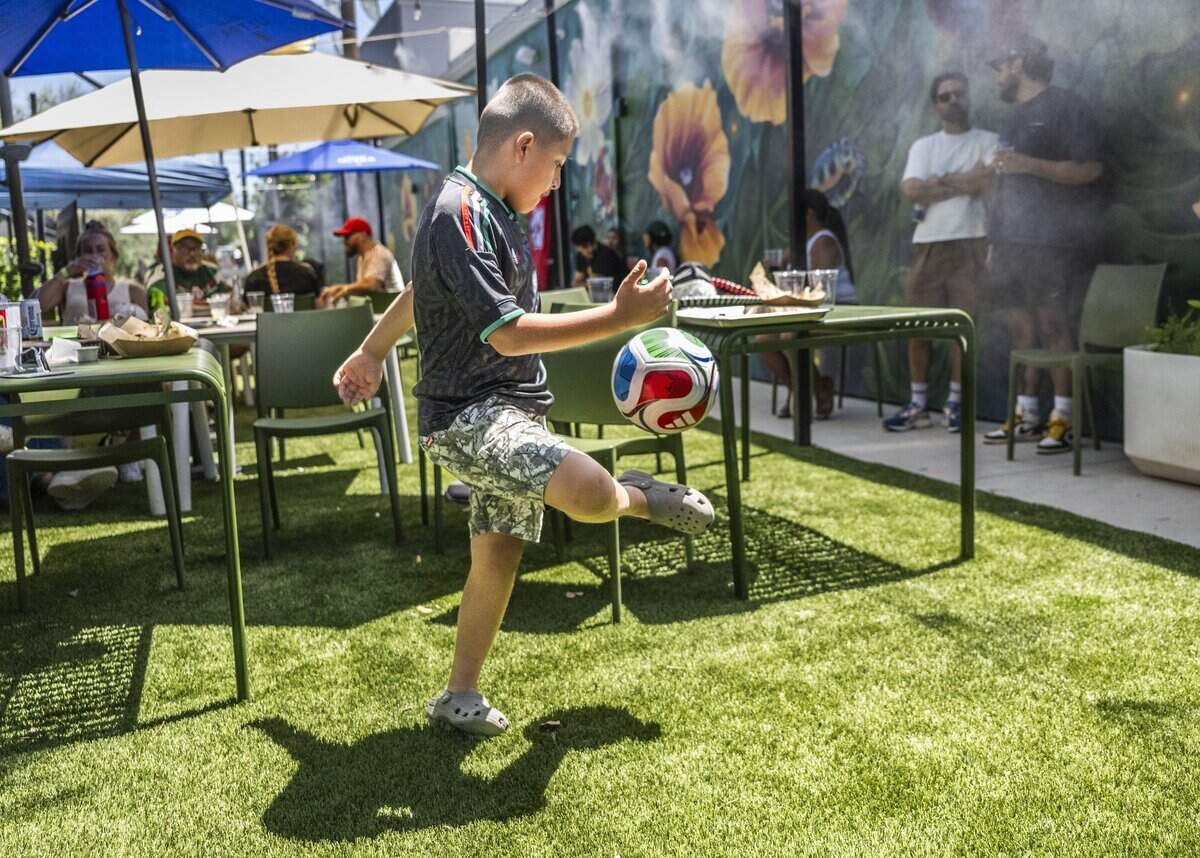 Noah Cruz, 7, of Sacramento plays with a World Cup soccer ball during a World Cup watch party at Garden at the Line in Sacramento on Thursday.