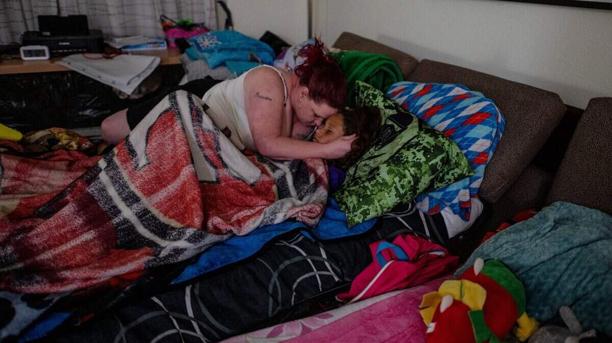 Kristi Phillips consuela a su hijo Tryree Franklin, de 11 años, quien no se sentía bien, en un sofá cama dentro del Residence Inn de Sacramento donde se alojaron en mayo de 2021. Phillips lleva más de 12 años en la lista de espera de vales de vivienda.
