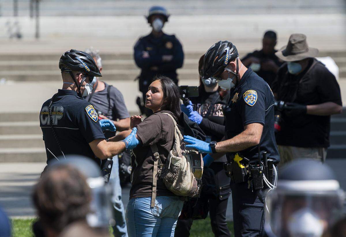 California Highway Patrol officers detain a protester during a demonstration at the Capitol in Sacramento on Friday, May 1, 2020, against Gov. Gavin Newsom’s stay-at-home order to slow the spread of the coronavirus.
