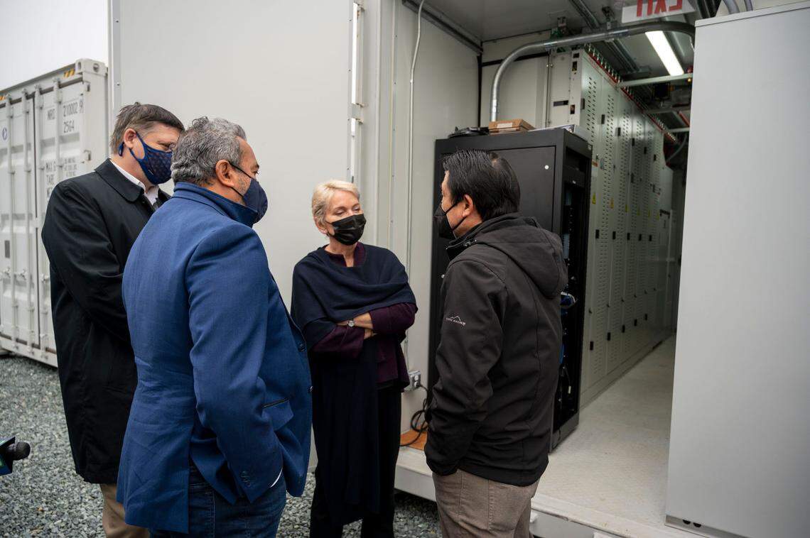 U.S. Energy Secretary Jennifer Granholm, looks at industrial-scale storage batteries while talking with SMUD CEO Paul Lau, right, and Congressman Ami Bera, left, on Friday. Battery storage is critical to reliability, she said, applauding SMUD’s construction of a small battery farm outside its training academy in south Sacramento.
