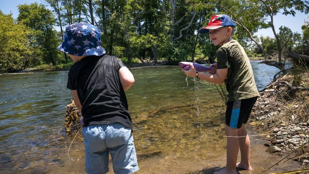 Six-year-old Carter Cheek, right, sprays his brother, 4-year-old Jasper, both of Sacramento, with cold American River water while playing at the William B. Pond Recreation Area in Carmichael on Saturday. Temperatures are expected to heat up this week in the region.