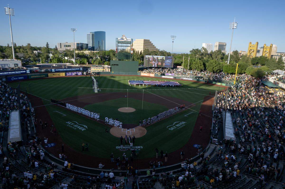 Athletics and Houston Astros players stand on the first and third base lines during the playing of the national anthem on Opening Day, on Friday, April 3, at Sutter Health Park in West Sacramento.