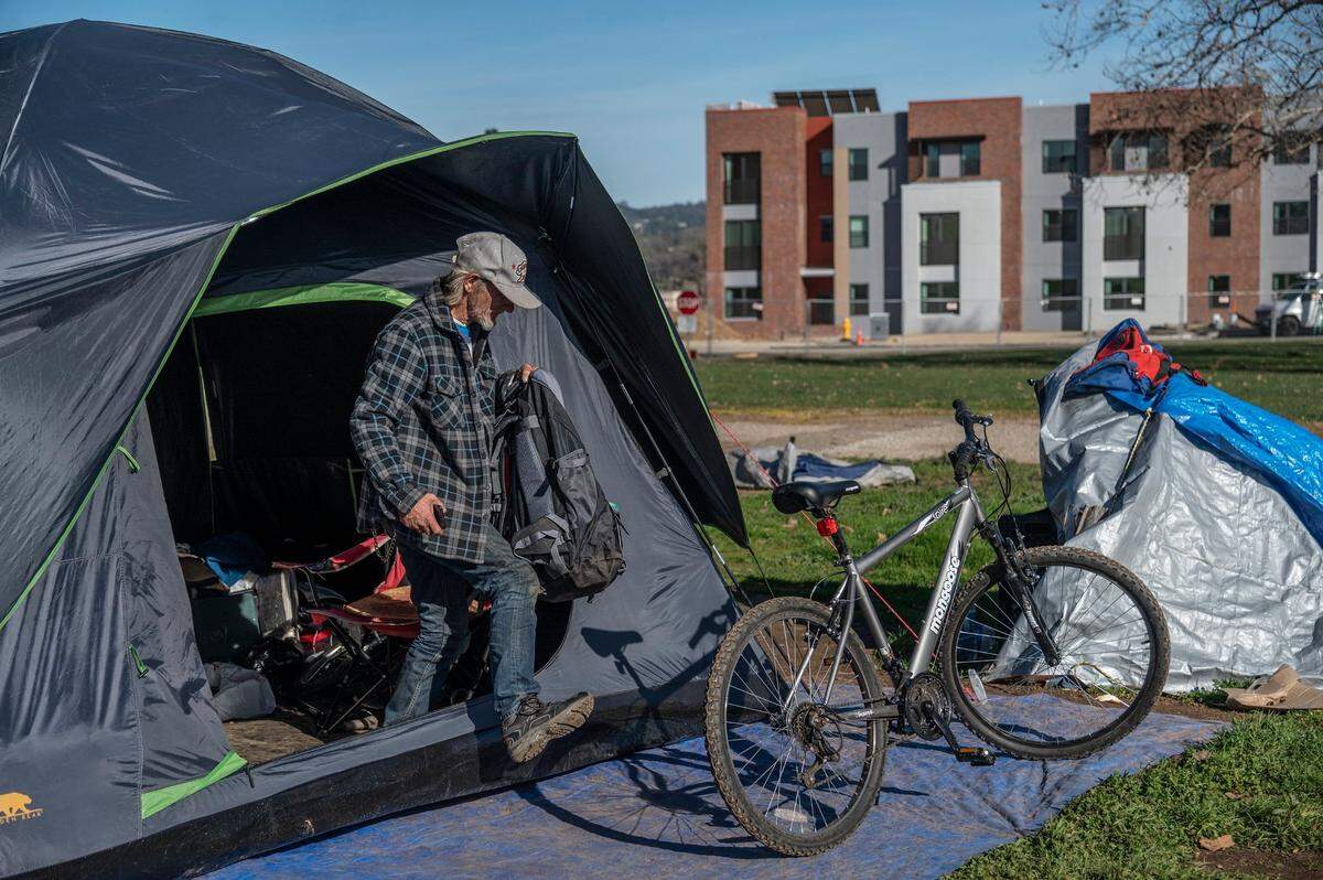 Roy Warren, 63, steps out of his tent at a homeless encampment across from new affordable housing apartments on Jan. 21, in Auburn. “If you do not have section 8 or are on a fixed income, their rent for those places is two thousand dollars,” he said. “There is no way any of us can afford that.”