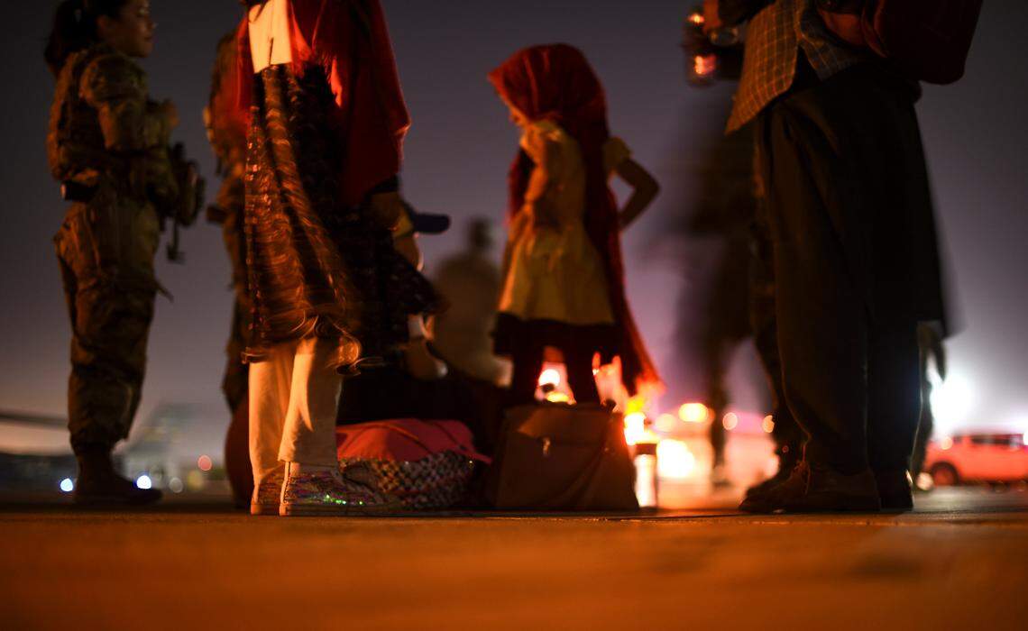 Afghan evacuees stand on the tarmac after arriving to Ali Al Salem Air Base, Kuwait, in 2021, during the evacuation of American citizens, special immigrant visa applicants and other at-risk individuals from Afghanistan.